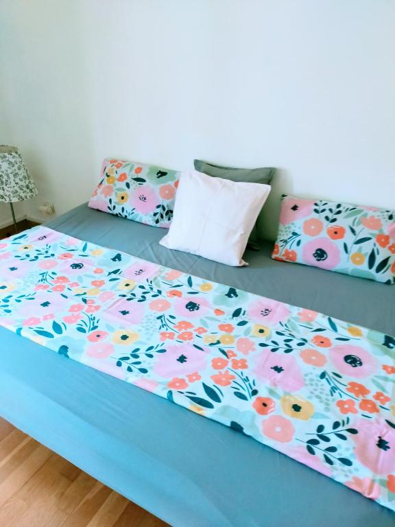 un lit bleu avec des draps et des oreillers fleuris dans l'établissement Esprit Nordik, à Avignon