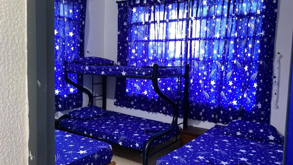a room with three bunk beds in front of a window with blue lights at casa maranatha in Melgar