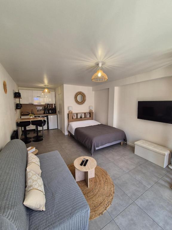 a bedroom with a bed and a couch and a tv at Studio Bohême chic à Disney in La Houssaye-en-Brie