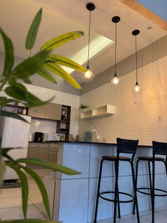 a kitchen with three bar stools and lights at Rodrigues AP Apartamento em Barreirinhas in Barreirinhas