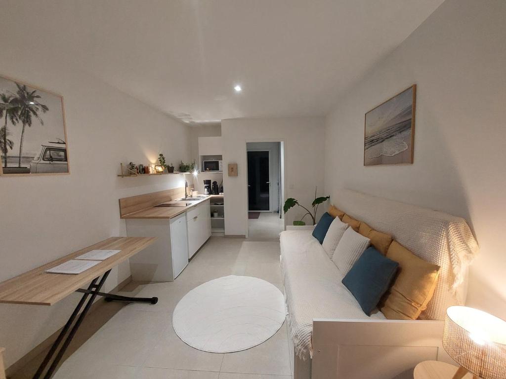 Una sala de estar con un sofá y una cocina. en Studio confort proche de la mer sur la côte d'Emeraude - Le Minihic sur Rance, en Le Minihic-sur-Rance