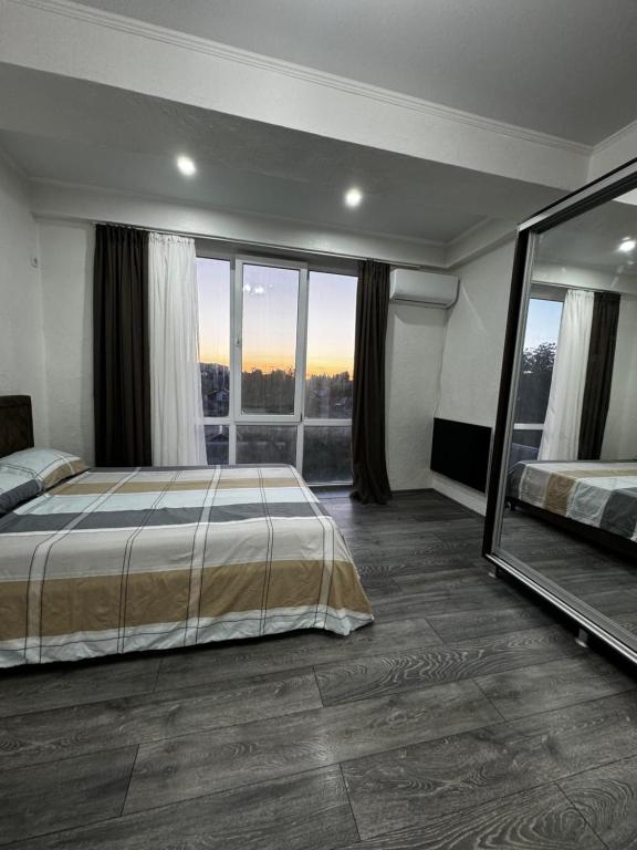 a bedroom with a bed and a large window at Rent&live calm place apartment in Crăsnăşeni