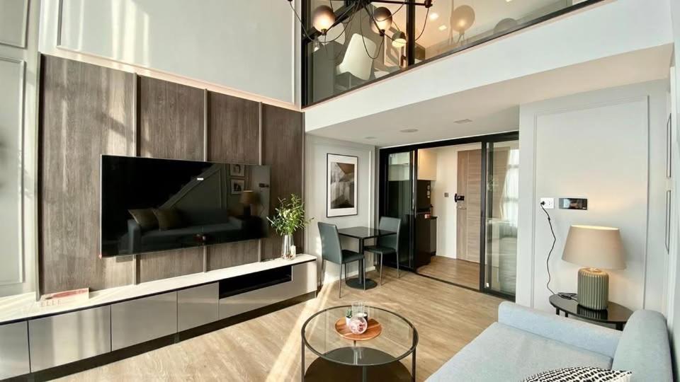een woonkamer met een bank en een tv bij Modiz Modiza Sukhumvit R4 in Bangkok