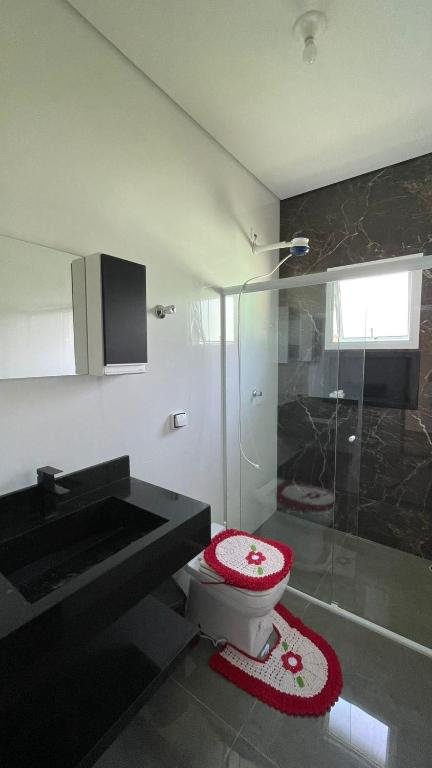 a bathroom with a toilet and a sink and a shower at Cantinho aconchego gc in Ubatuba