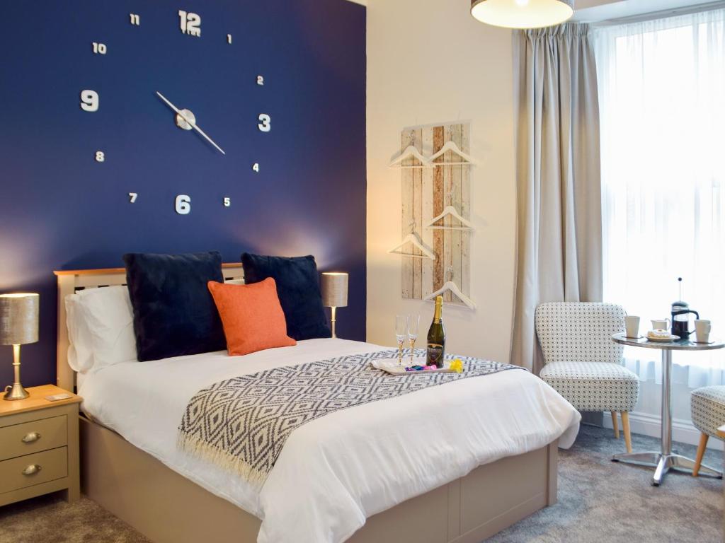ein Schlafzimmer mit einem Bett mit einer Uhr an der Wand in der Unterkunft Little Fishes in Tenby