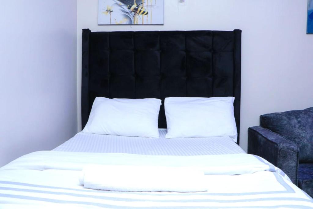 ein Bett mit einem schwarzen Kopfteil und zwei Kissen in der Unterkunft Betty Homes in Nairobi