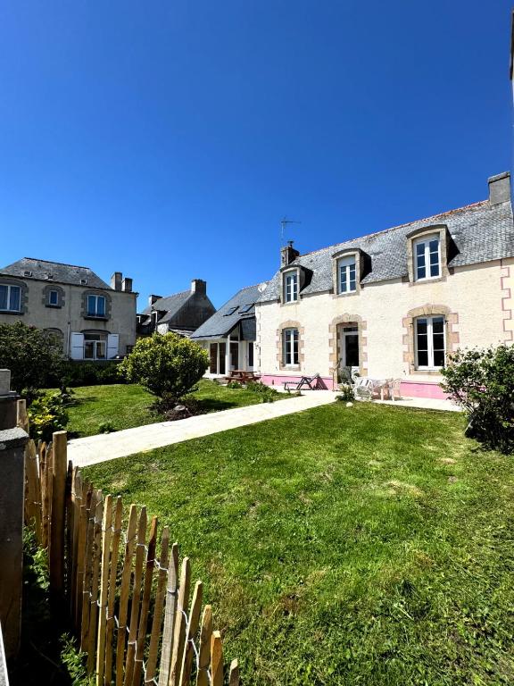 une maison avec une clôture devant une cour dans l'établissement Les pieds dans l eau, à Penmarcʼh