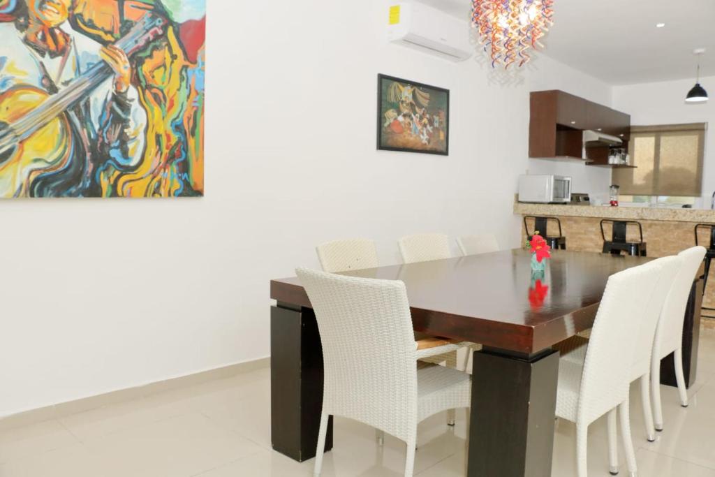 a dining room with a table and white chairs at Oasis del Sol in Playa del Carmen