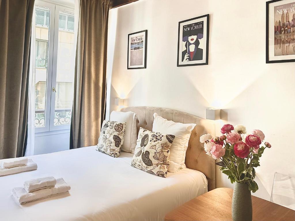 a bedroom with a white bed and a vase of flowers at Mondétour Paris centre - Urban flat in Paris