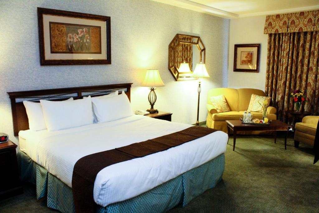 een hotelkamer met een groot bed en een bank bij University Square Hotel in Fresno