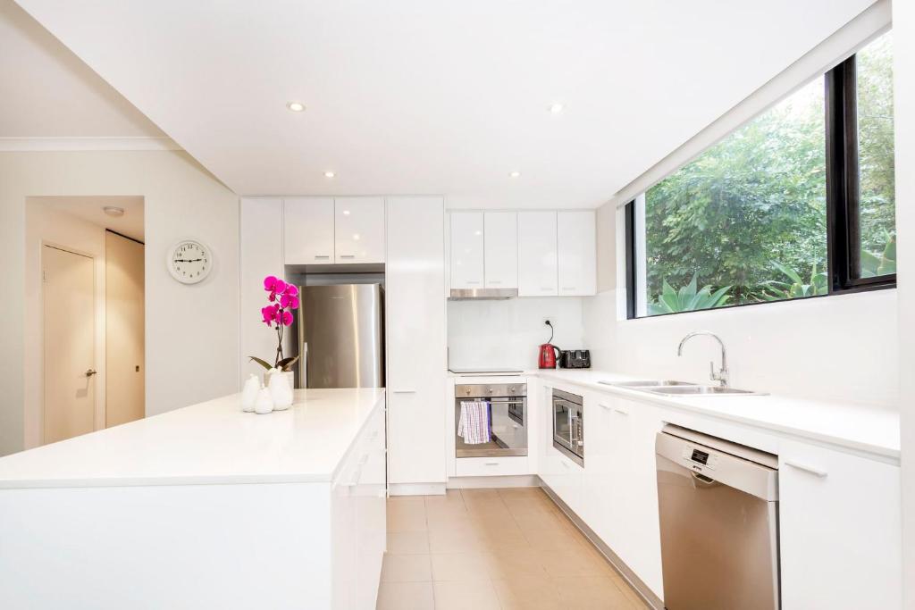 a kitchen with white counters and a large window at Subiaco Rooftop on Sheen in Perth