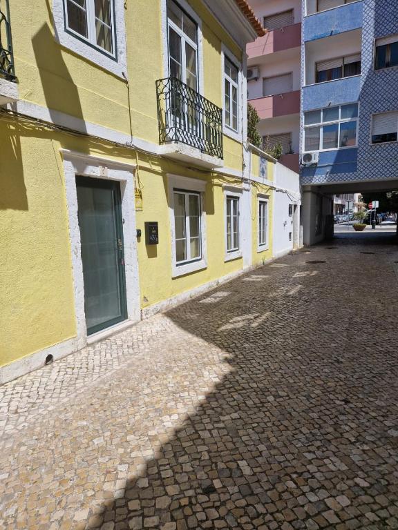 a yellow building on a cobblestone street at Casa 7 in Setúbal