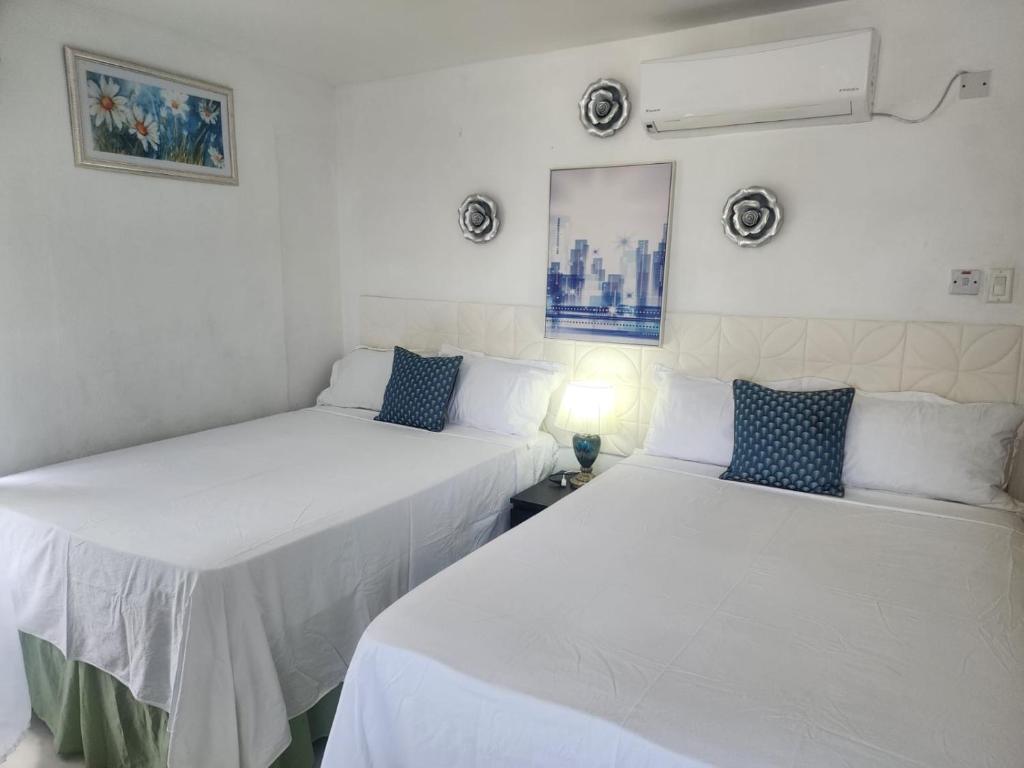 two beds in a room with white walls at Pearl of The City BLUE PEARL in Kingston