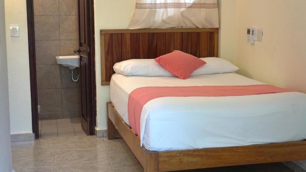 a bedroom with a bed with a red pillow on it at Bacanda Hotel in Puerto Escondido