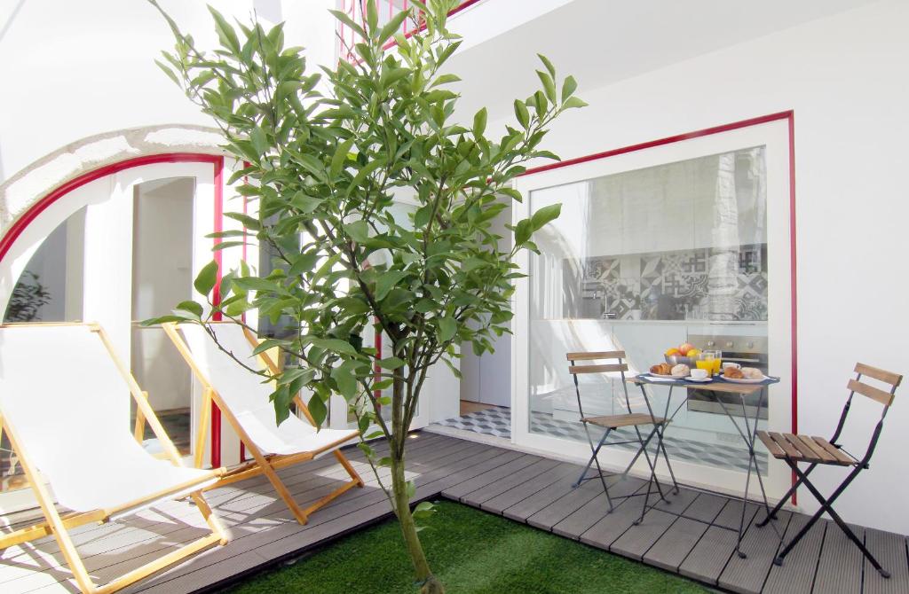 een veranda met een boom, stoelen en een tafel bij HM - The Garden in Porto