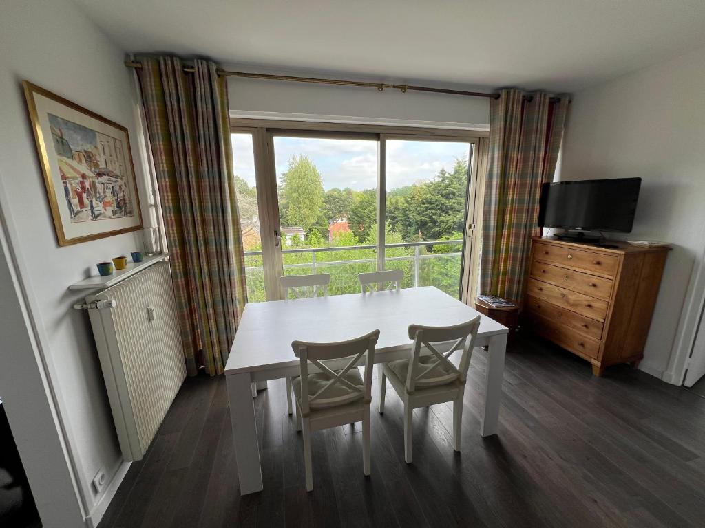 ein Esszimmer mit Tisch und Stühlen und einem Fenster in der Unterkunft Arsène 3 l'Hermitage in Le Touquet-Paris-Plage