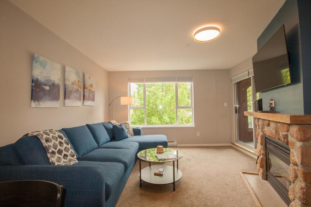 a living room with a blue couch and a fireplace at 2BR Deer Lodge, Epic Location, Private Covered Patio, Free Parking in Whistler