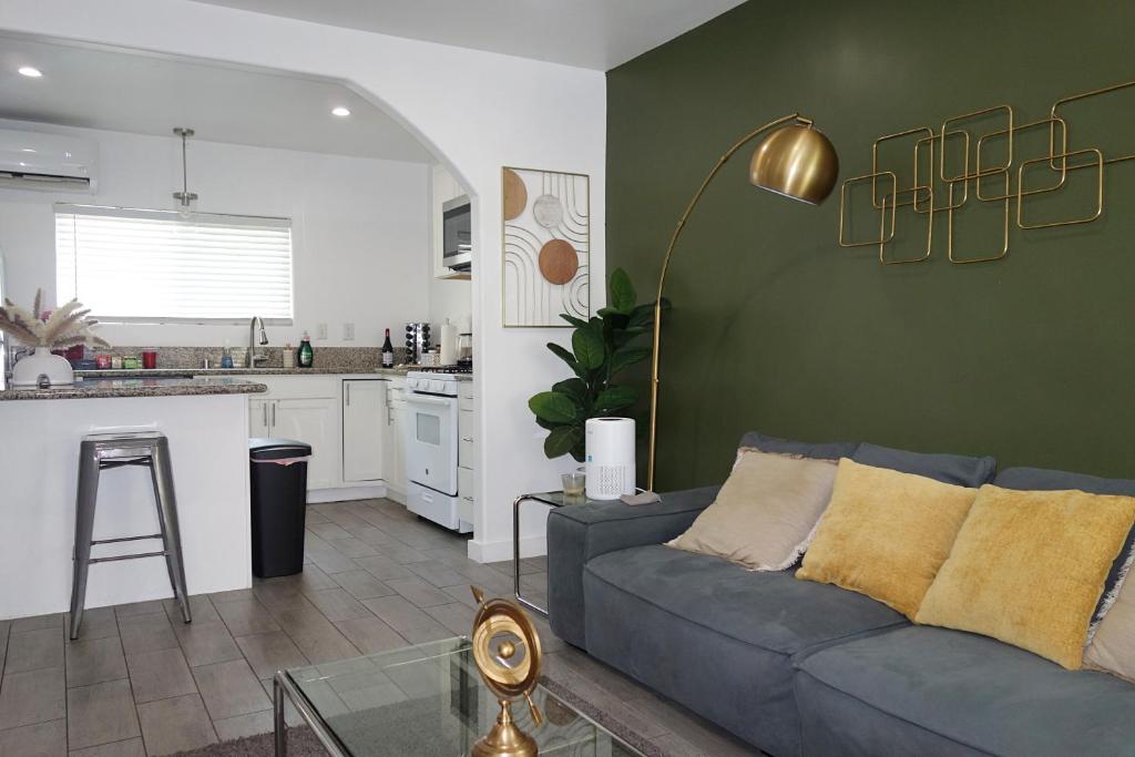 a living room with a blue couch and a kitchen at Casa Mid City - Centrally Located 1BR Getaway with Private Yard in Los Angeles