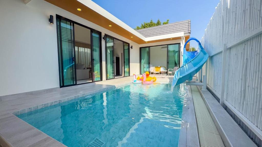 a swimming pool with a slide in front of a house at Wana Villa ChaAM in Nikhom Sang Ton Eng Khuan Phet