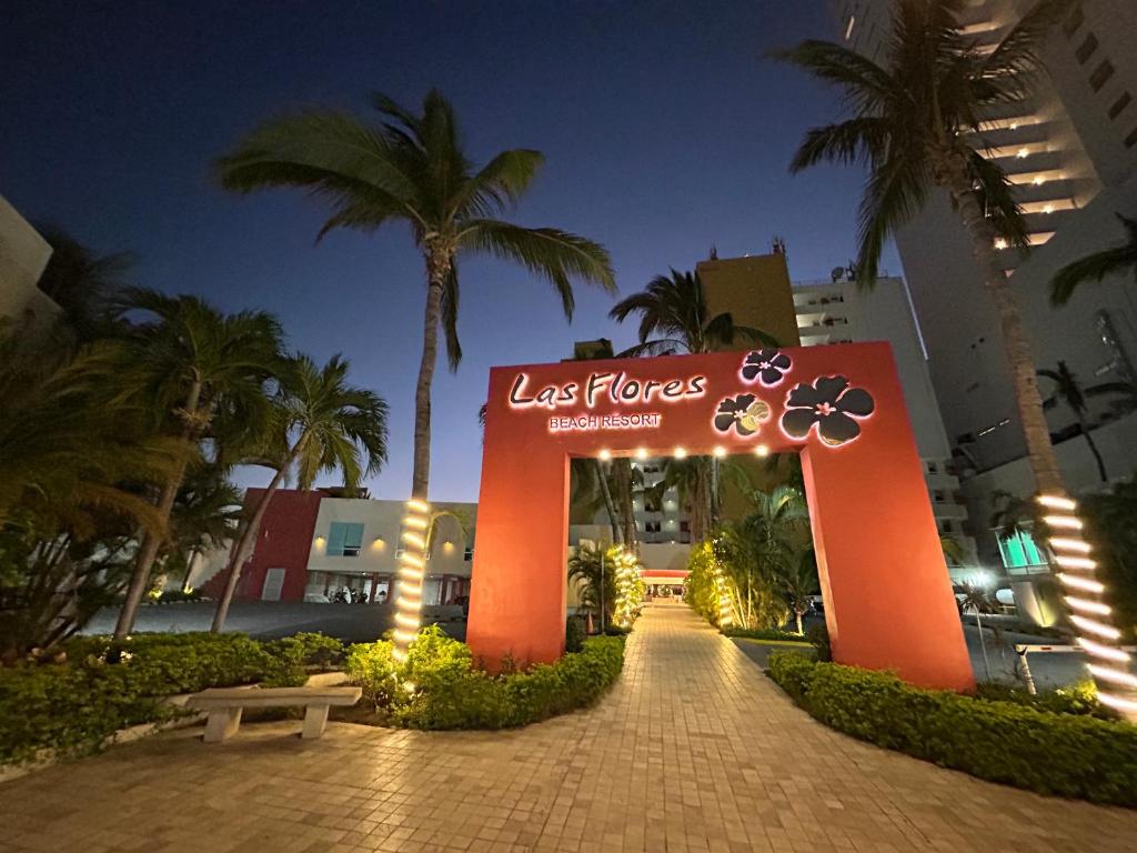 Un cartel a la entrada de un complejo turístico por la noche. en Las Flores Beach Resort, en Mazatlán