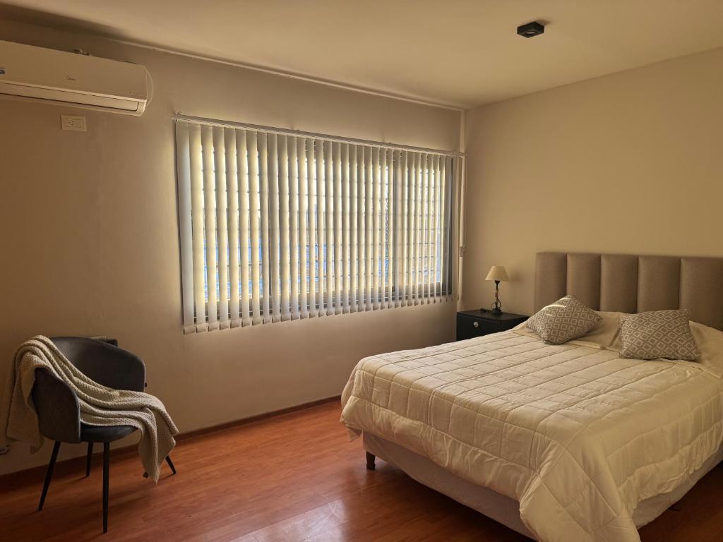 a bedroom with a bed and a chair and a window at Duplex premium in La Porteña