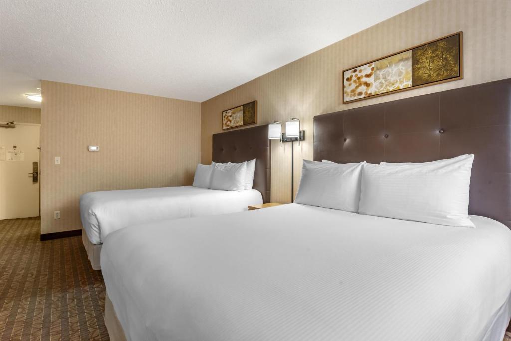 two beds in a hotel room with white pillows at Best Western Cold Lake Inn in Cold Lake