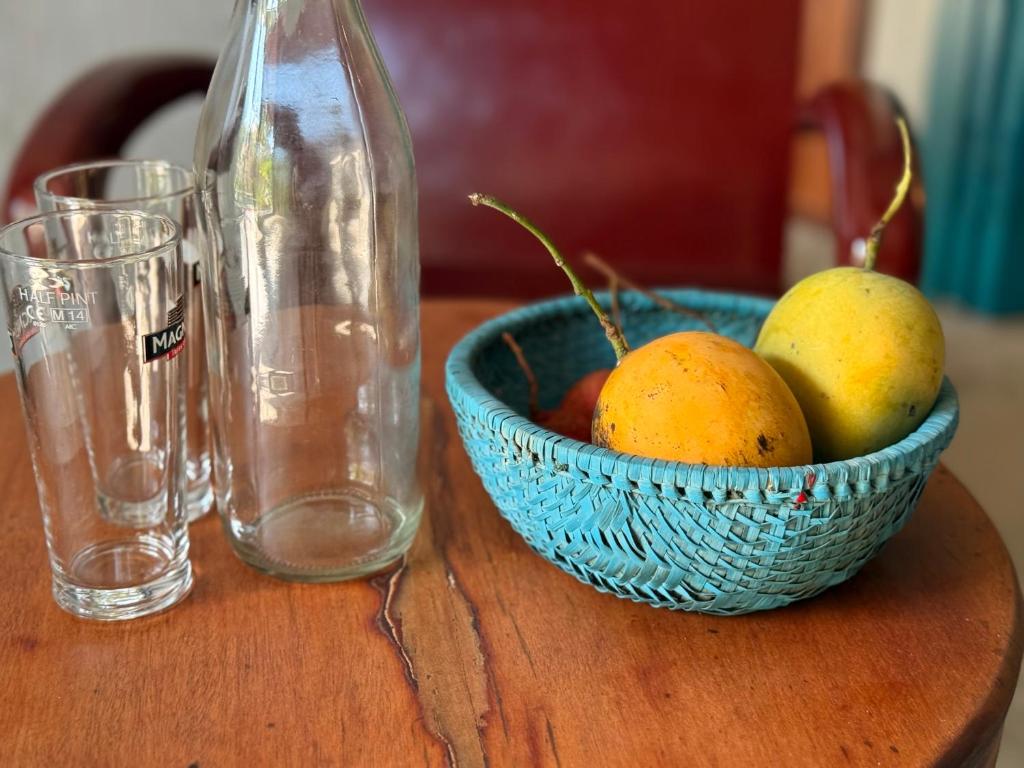 - un bol de fruits sur une table avec une bouteille et des verres dans l'établissement The Paddys Home, à Hiếu Nhơn