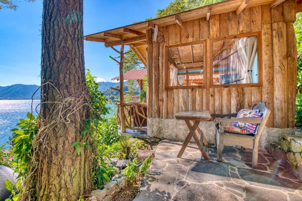 a wooden house with a bench and a table at Magical lakeview Casita, swim dock, sauna, kitchen in San Marcos La Laguna