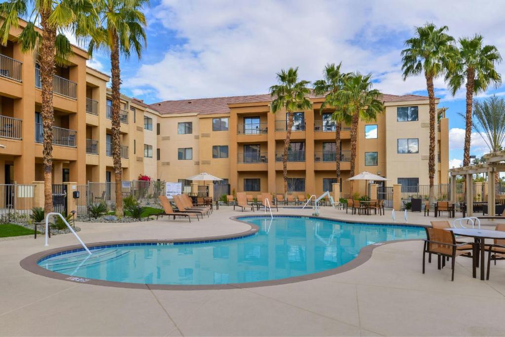 a pool with tables and chairs in front of a building at Courtyard Palm Desert in Palm Desert