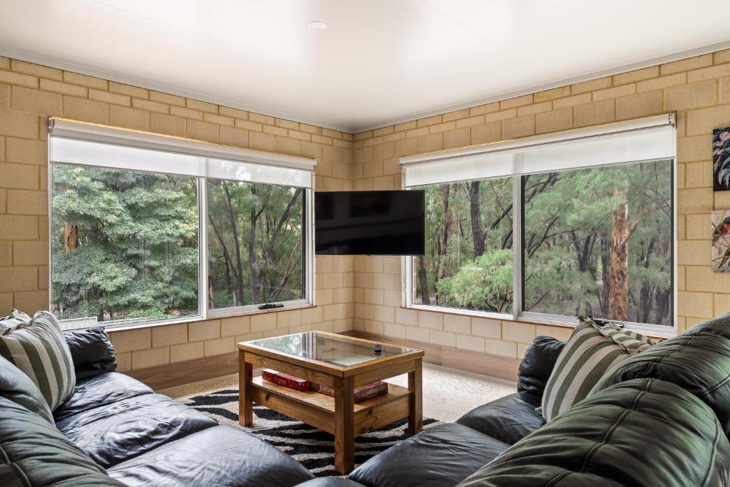 Una sala de estar con un sofá y dos ventanas. en Arcadia Dreaming Chalet Margaret River, en Margaret River Town