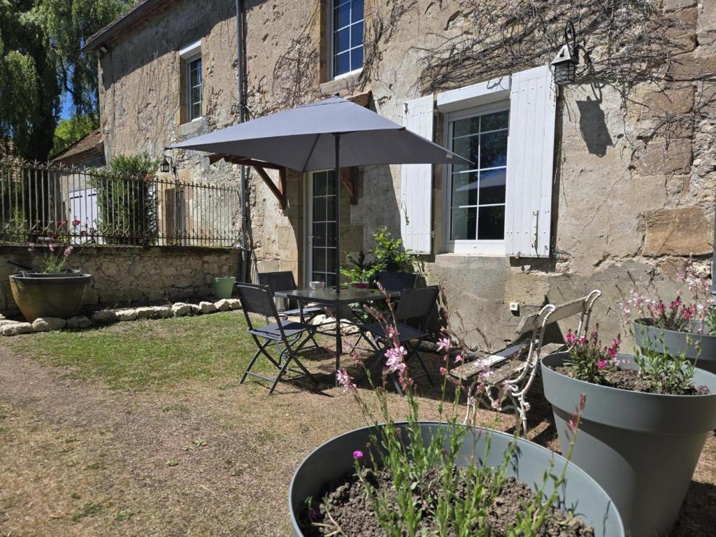 a table and chair under an umbrella in a yard at Gîte de charme à Souvigny avec jardin et animaux admis - FR-1-489-581 in Souvigny