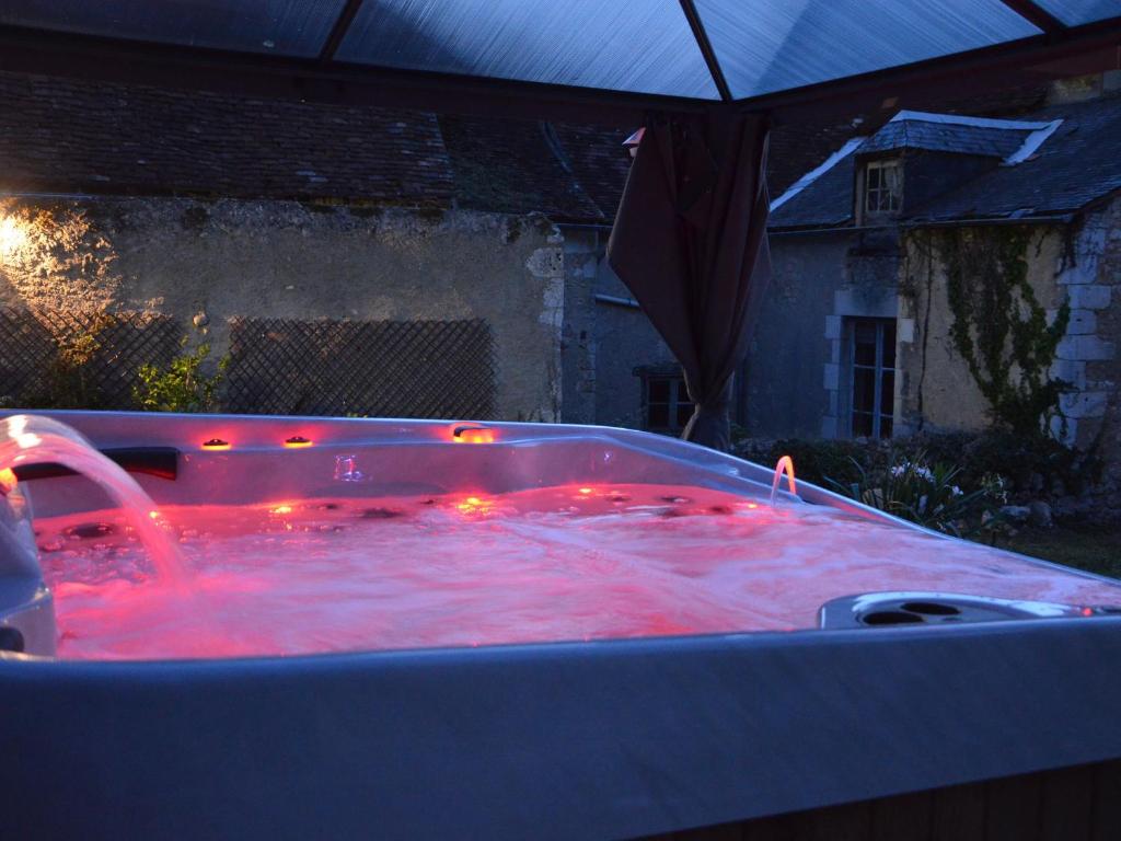 - un bain à remous avec des lumières rouges dans la cour dans l'établissement Charmant gîte au cœur du Berry avec jacuzzi et terrasse - FR-1-591-757, à Le Blanc