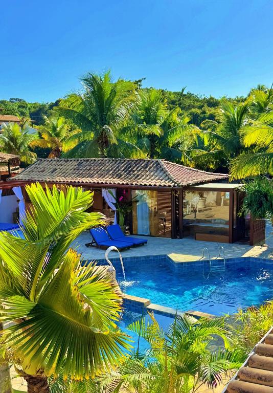 a house with a swimming pool with palm trees at Villa Baobá Pousada & Spa in Búzios