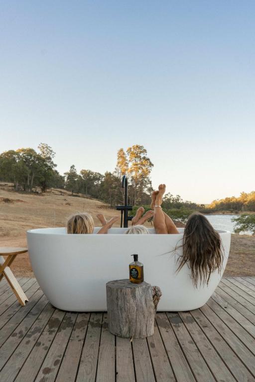 three women laying in a bath tub on a wooden deck at Tiny Matilda in Bridgetown