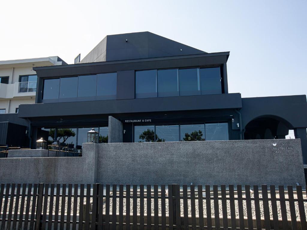 une maison noire avec une clôture devant elle dans l'établissement ONCRI-Karatsu おんくり唐津, à Karatsu