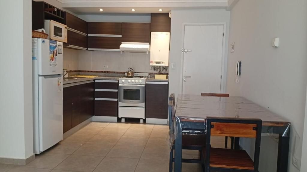 een keuken met houten kasten en een witte koelkast bij Exelente departamento en Carlos Paz in Villa Carlos Paz