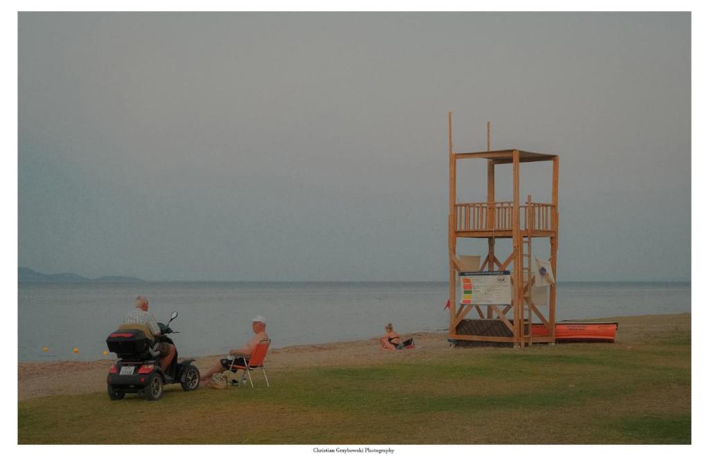 a man riding a scooter on the beach with a lifeguard tower at Elizas house in Nea Makri