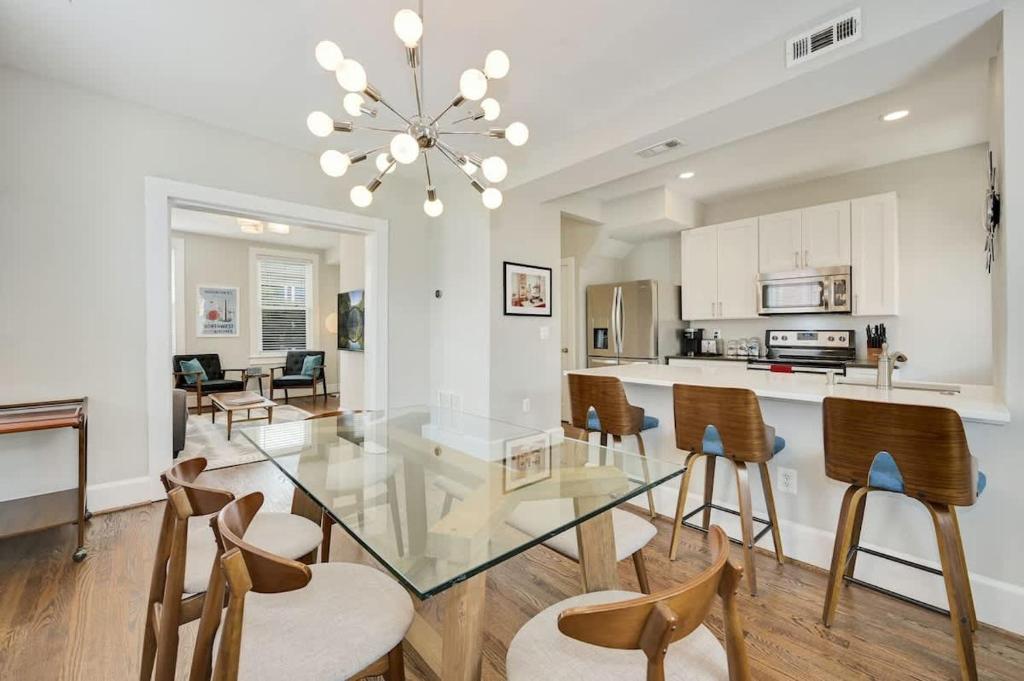 a dining room and kitchen with a glass table and chairs at Mid-Century Townhome Steps from Restaurants #DCottage in Washington