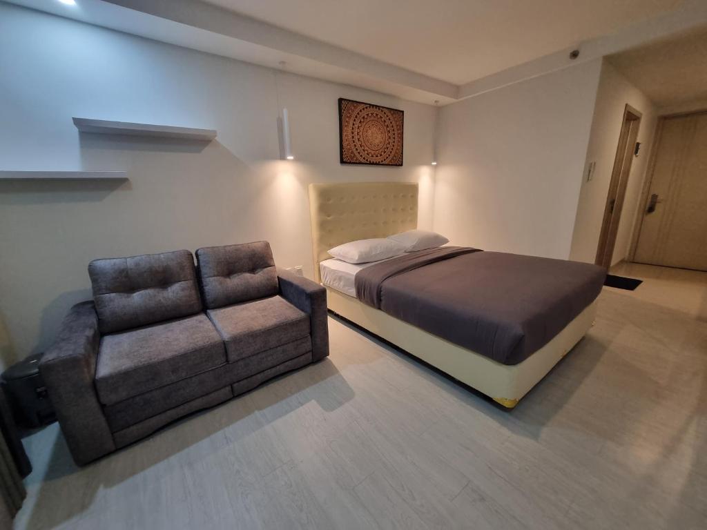 a bedroom with a bed and a couch and a chair at Studio Room Apartment with Pool in Yogyakarta