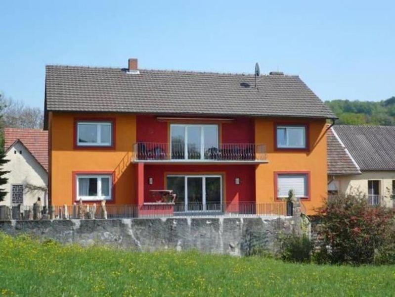 a red and orange house with a balcony at Ferienwohnung beim Steinmetzmeister im Quarzwerk in Lautertal