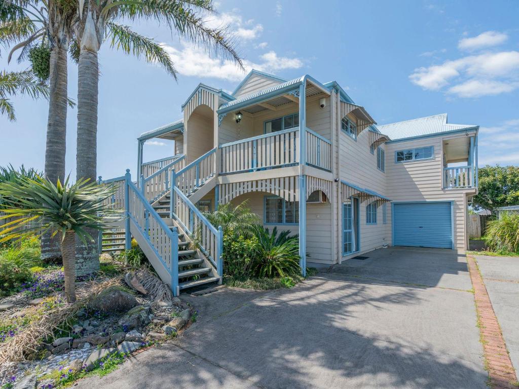 Una casa grande con palmeras al frente. en Charming Family Retreat - Cozy 3 Bedroom & 3 Bathroom, en Whitianga
