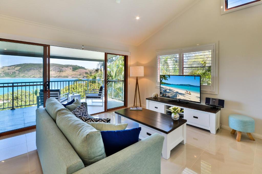 a living room with a couch and a tv at Heliconia Grove - 1 bedroom - on Hamilton Island by HIHA in Hamilton Island