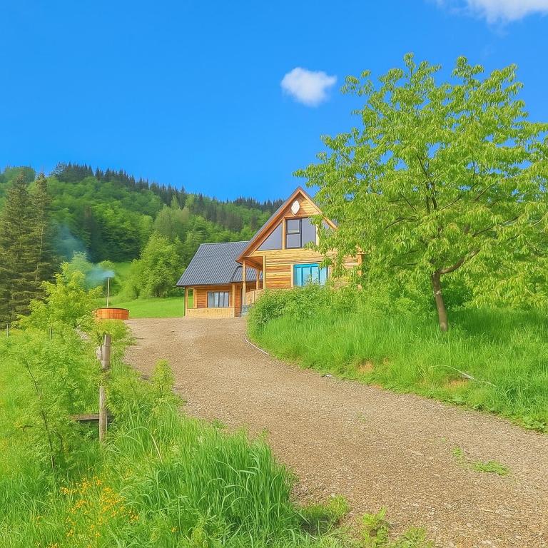 a house with a dirt road next to a tree at Căsuța de la munte in Bistriţa