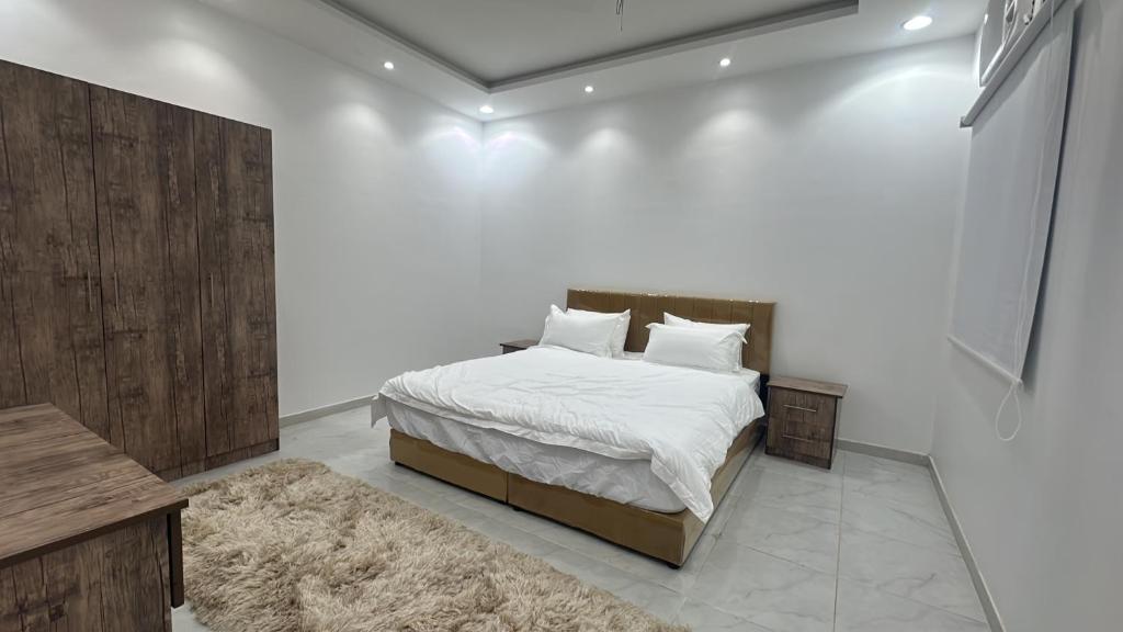 a bedroom with a bed and a white wall at شقة جديدة ثلاث غرف نوم داخل حدود الحرم in Al Madinah