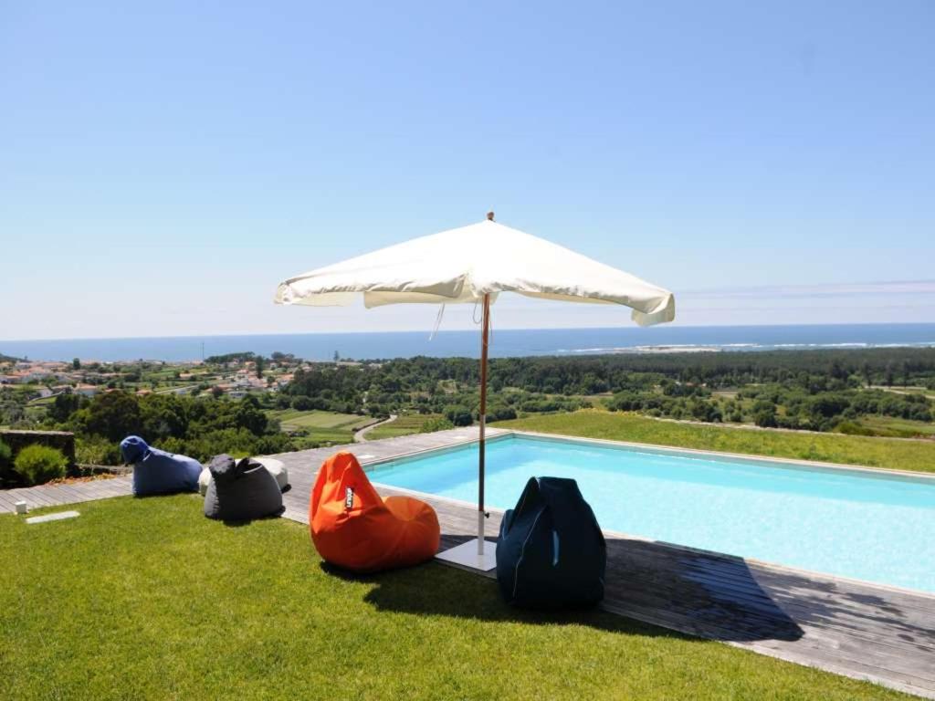 ein Sonnenschirm und Stühle neben einem Swimmingpool in der Unterkunft Stunning Caminha Villa 3 Bedrooms Villa Gagusta Beautiful Sea & Beach in Caminha