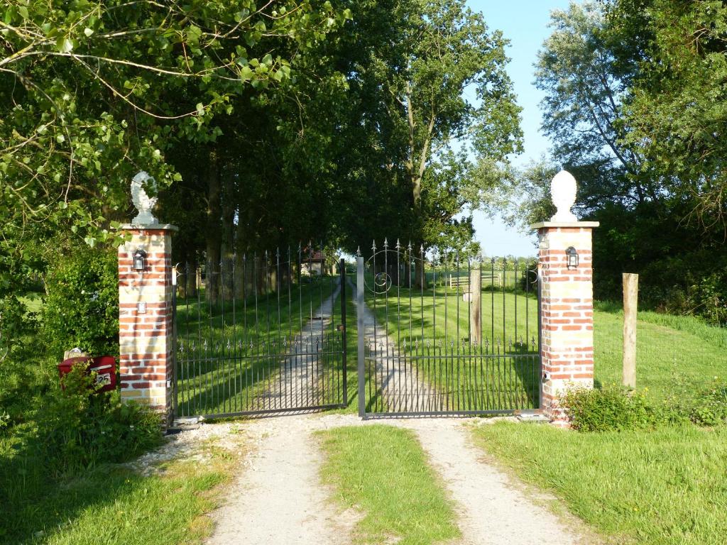 a gate in a field with a dirt road at Paardenhof Guesthouse in Esquelbecq