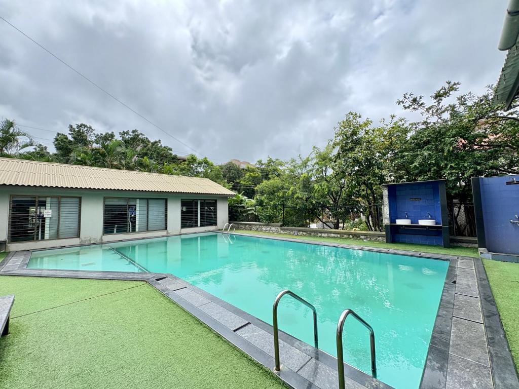 een zwembad met blauw water voor een huis bij HoneyBee Resort Lonavala in Lonavala