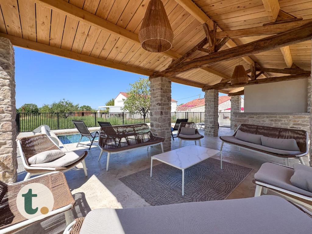 d'une terrasse avec des canapés et des chaises sous un plafond en bois. dans l'établissement Tranquiloue - La Maison de Gabriel - Puy du Fou, aux Herbiers