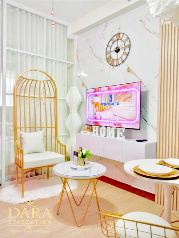 a living room with a tv and a table and chairs at Affordable Condo Near Malls in Quezon City in Manila