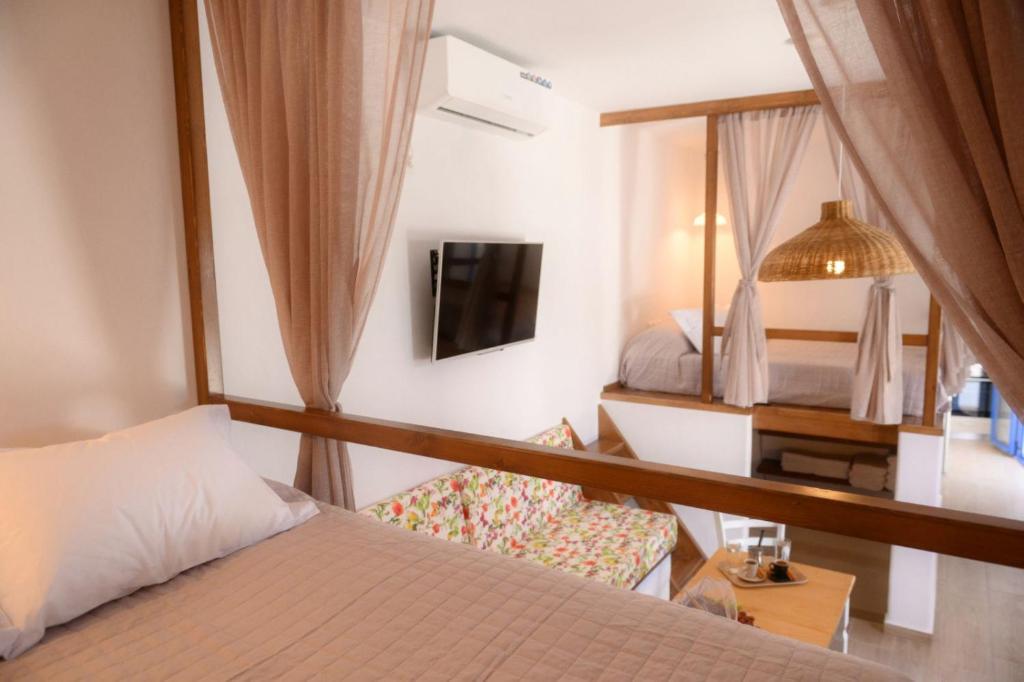 1 dormitorio con 1 cama, TV y espejo en Exoxiko Summer House, en Myrties